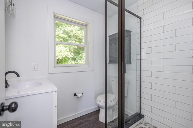 bathroom featuring an enclosed shower, vanity, toilet, and hardwood / wood-style floors