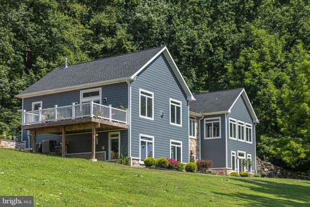 rear view of house featuring a wooden deck, cooling unit, and a yard