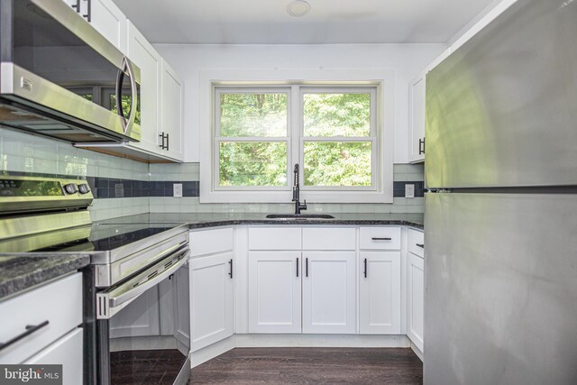 kitchen with white cabinets, sink, dark stone countertops, and stainless steel appliances