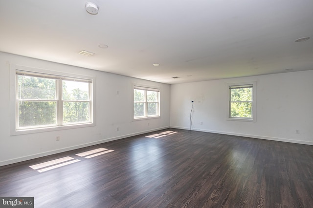 empty room with dark wood-type flooring and a wealth of natural light