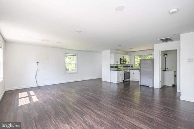 unfurnished living room with dark hardwood / wood-style flooring and a healthy amount of sunlight