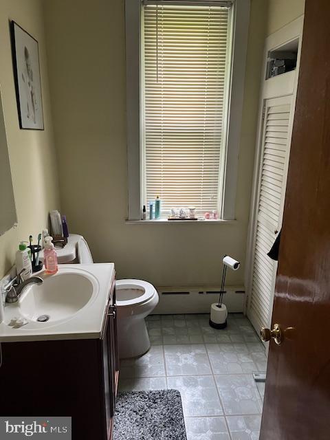 bathroom featuring tile flooring, a baseboard radiator, toilet, and large vanity