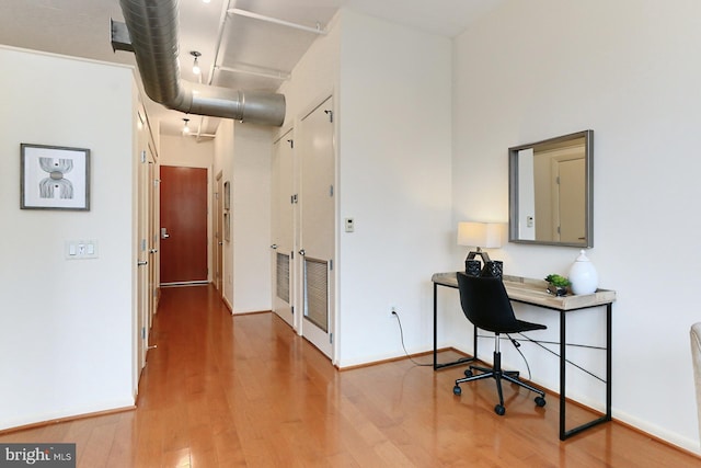 home office with a high ceiling and wood-type flooring