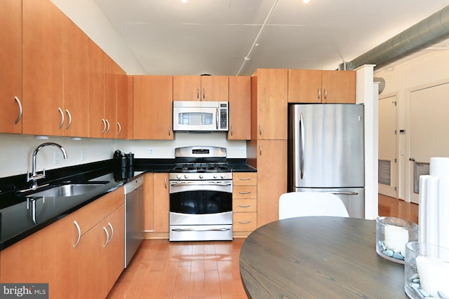 kitchen with appliances with stainless steel finishes, sink, and light hardwood / wood-style flooring