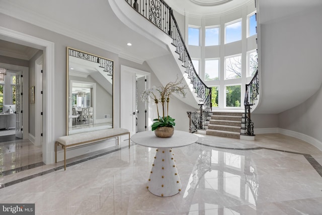 tiled entrance foyer featuring plenty of natural light, crown molding, and a high ceiling