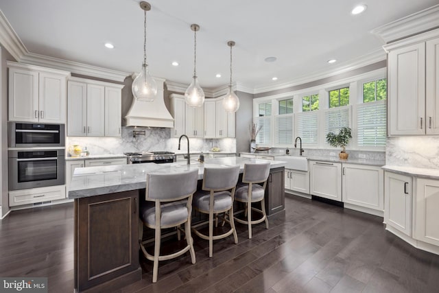 kitchen featuring backsplash, pendant lighting, a kitchen island with sink, and dark hardwood / wood-style floors