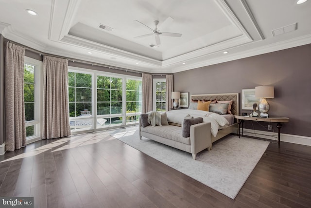 bedroom with dark hardwood / wood-style flooring, ceiling fan, crown molding, and a tray ceiling