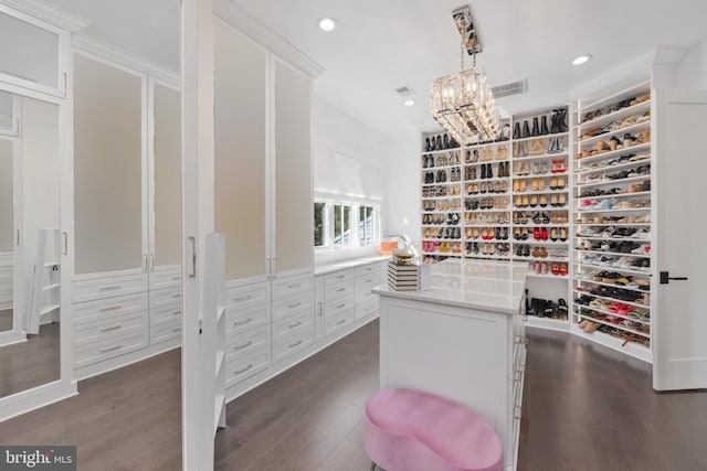 walk in closet with an inviting chandelier and dark hardwood / wood-style flooring