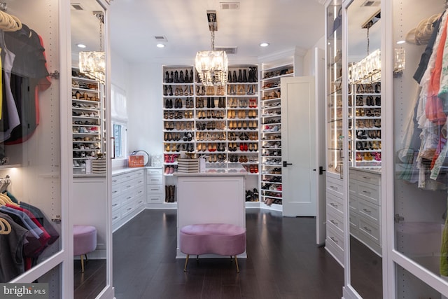 walk in closet with a chandelier and dark hardwood / wood-style flooring