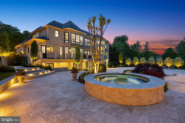 pool at dusk featuring central air condition unit and a patio