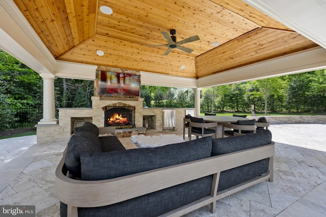 view of patio with an outdoor living space with a fireplace and ceiling fan