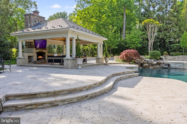 view of pool featuring exterior fireplace, a gazebo, and a patio area