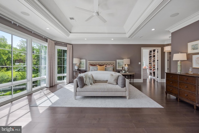 bedroom with ceiling fan, a tray ceiling, dark wood-type flooring, and crown molding