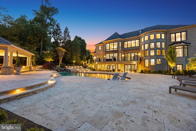 pool at dusk featuring a patio area