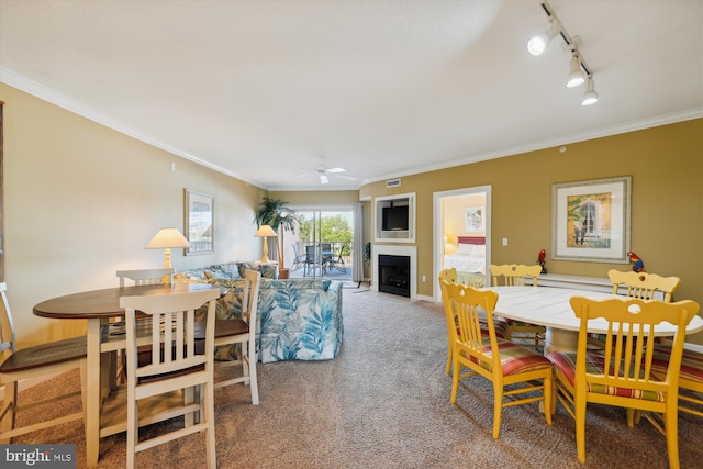 carpeted dining space featuring ornamental molding, ceiling fan, and rail lighting