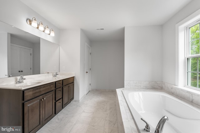 bathroom with vanity and tiled tub