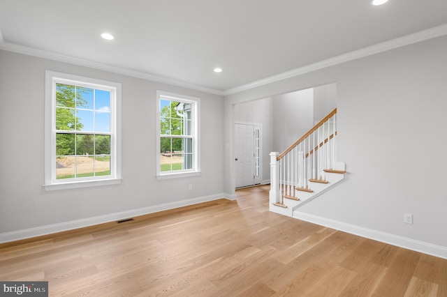 foyer with ornamental molding and light hardwood / wood-style floors