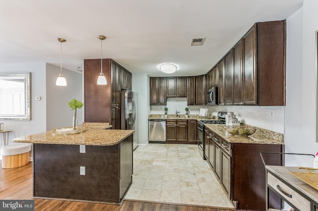 kitchen featuring light stone counters, stainless steel appliances, light hardwood / wood-style floors, pendant lighting, and sink