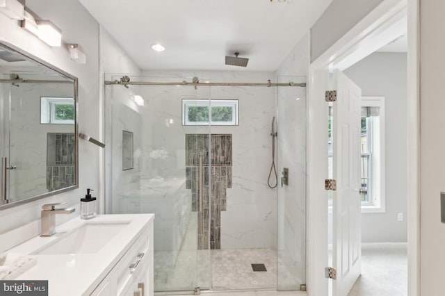 bathroom featuring a shower with door and vanity