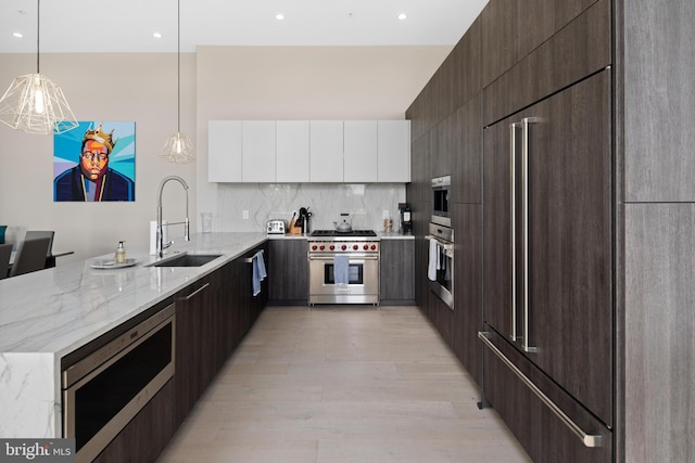 kitchen with built in appliances, light hardwood / wood-style flooring, hanging light fixtures, and backsplash