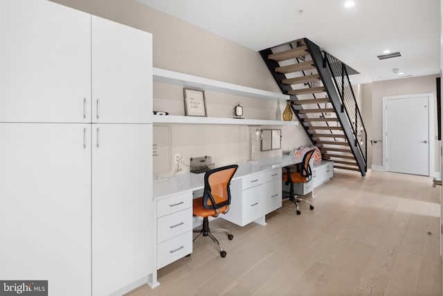 office with light wood-type flooring and built in desk