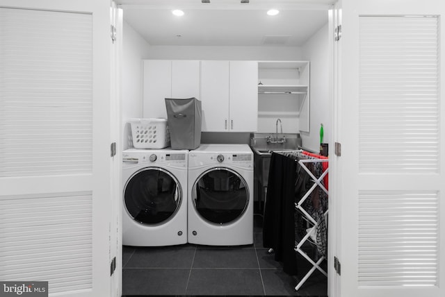 clothes washing area featuring cabinets, washing machine and clothes dryer, and dark tile patterned flooring