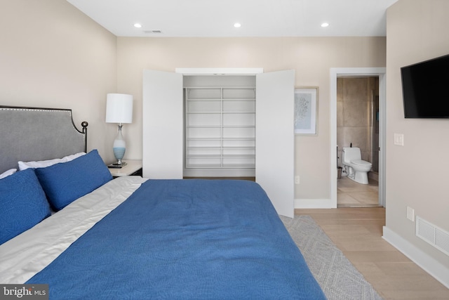 bedroom with a closet, light wood-type flooring, and ensuite bathroom