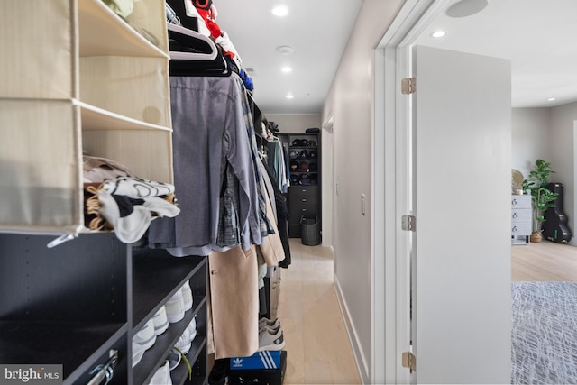 walk in closet with light hardwood / wood-style flooring