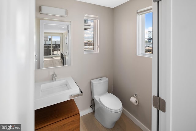 bathroom featuring hardwood / wood-style floors, a wall unit AC, sink, and toilet