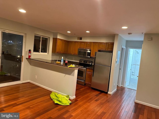 kitchen featuring kitchen peninsula, stainless steel appliances, and dark hardwood / wood-style floors