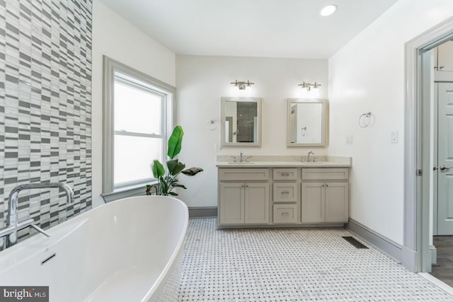 bathroom with a bathing tub, tile floors, vanity with extensive cabinet space, and double sink