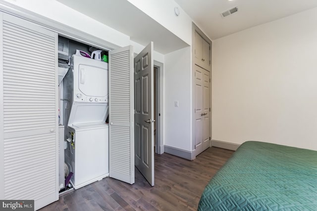 laundry area with dark hardwood / wood-style flooring and stacked washing maching and dryer