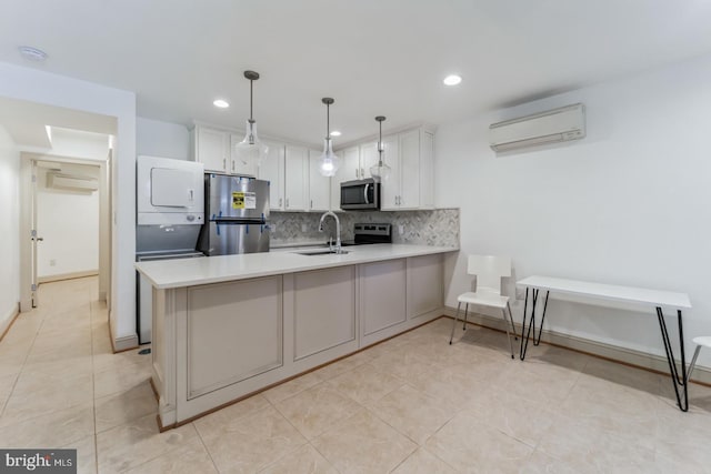 kitchen featuring hanging light fixtures, stainless steel appliances, stacked washer / drying machine, an AC wall unit, and light tile floors