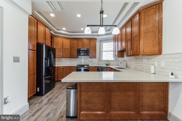 kitchen featuring kitchen peninsula, decorative light fixtures, light hardwood / wood-style flooring, black appliances, and sink