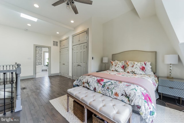 bedroom featuring multiple closets, ceiling fan, dark wood-type flooring, and vaulted ceiling with beams