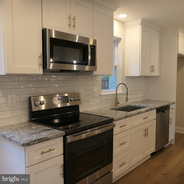 kitchen featuring white cabinets, stainless steel appliances, light stone countertops, and sink