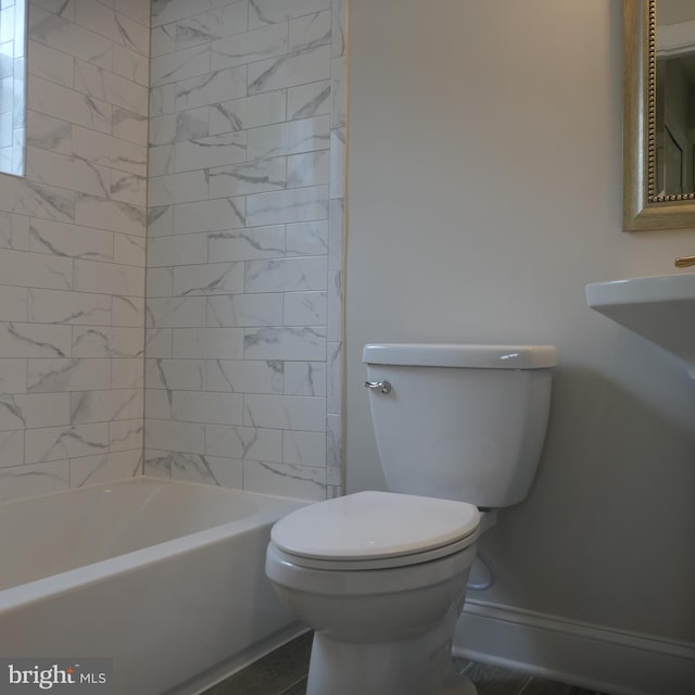 bathroom with toilet and tiled shower / bath