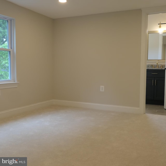 spare room featuring light colored carpet and sink