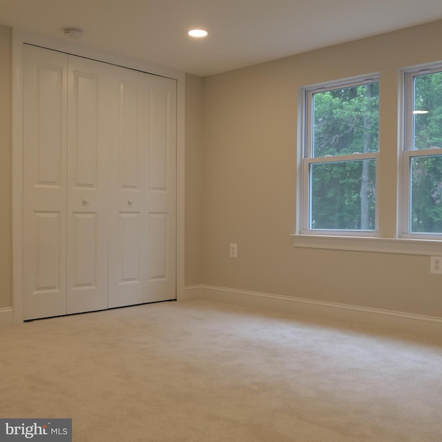 unfurnished bedroom featuring a closet, light colored carpet, and multiple windows