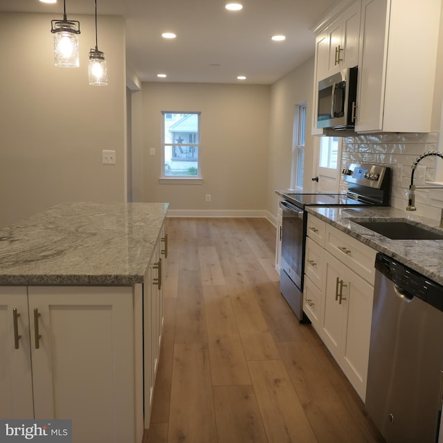 kitchen with sink, decorative light fixtures, decorative backsplash, white cabinets, and appliances with stainless steel finishes