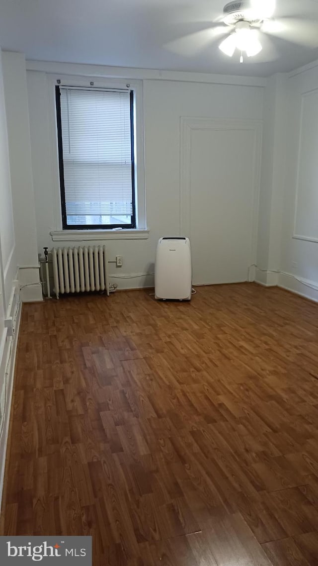 unfurnished room with radiator, ceiling fan, and dark hardwood / wood-style flooring