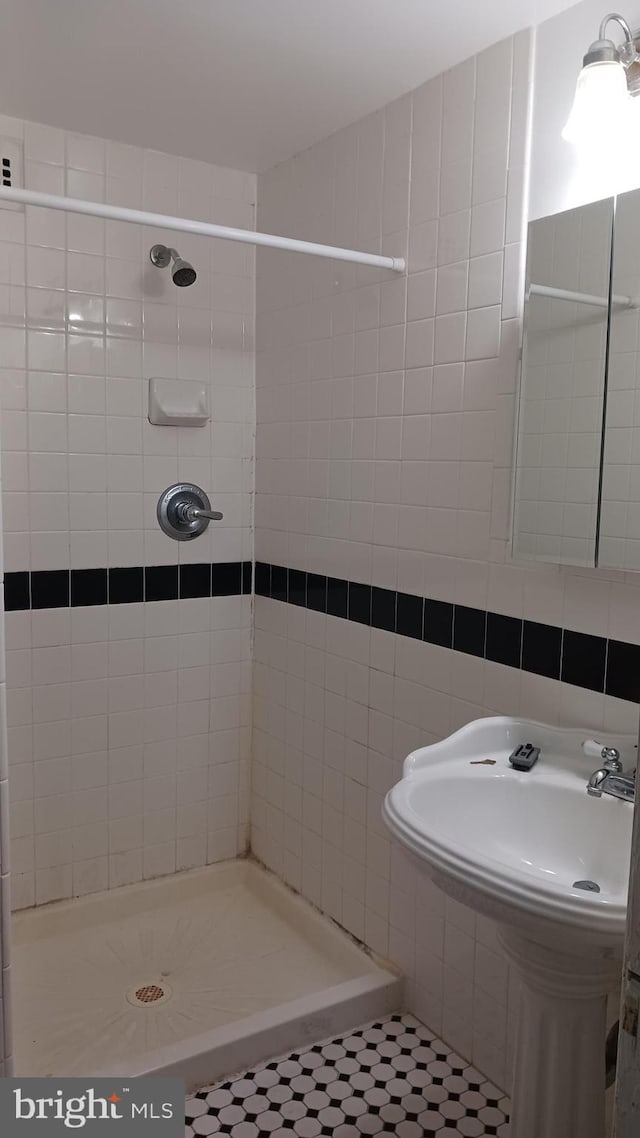 bathroom featuring tile patterned floors, a tile shower, tile walls, and tasteful backsplash