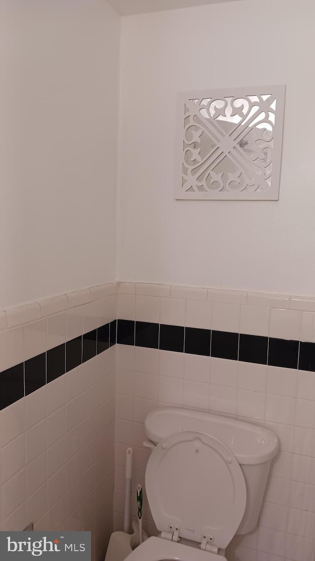 bathroom featuring toilet and tile walls