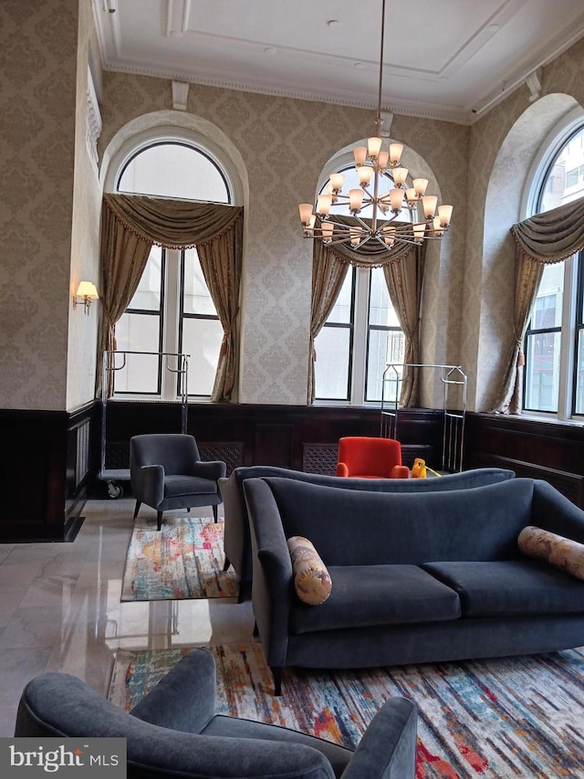 living room featuring a healthy amount of sunlight, a chandelier, and ornamental molding