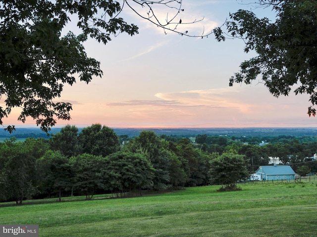 yard at dusk featuring a rural view