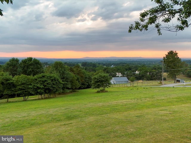 yard at dusk featuring a rural view