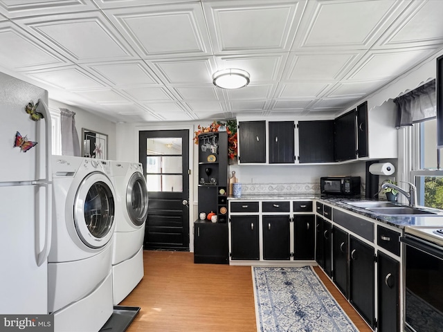 laundry room featuring sink, washing machine and dryer, and light wood-type flooring