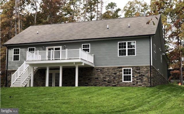 rear view of house with french doors, a wooden deck, and a lawn