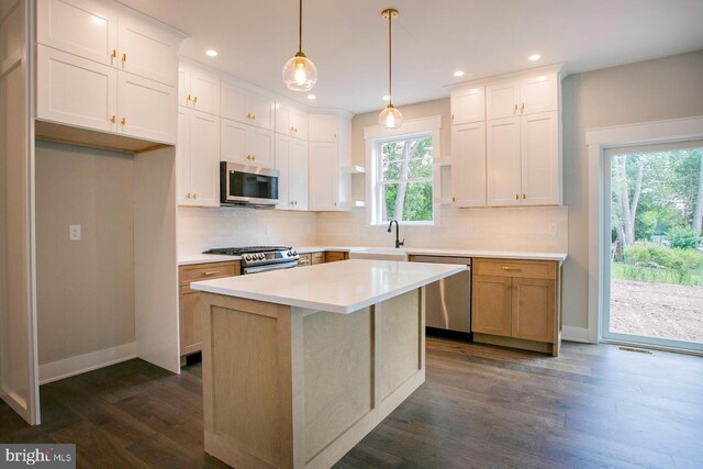 kitchen featuring white cabinets, dark hardwood / wood-style floors, a center island, and appliances with stainless steel finishes