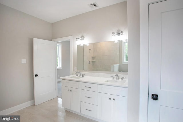 bathroom featuring vanity, a healthy amount of sunlight, and tiled shower